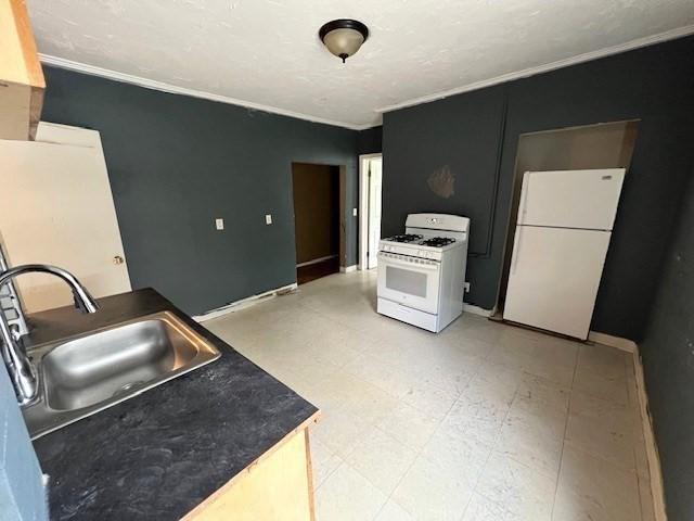 14 Felton St, Fitchburg, MA 01420 - kitchen with white appliances, ornamental molding, light flooring, and dark countertops