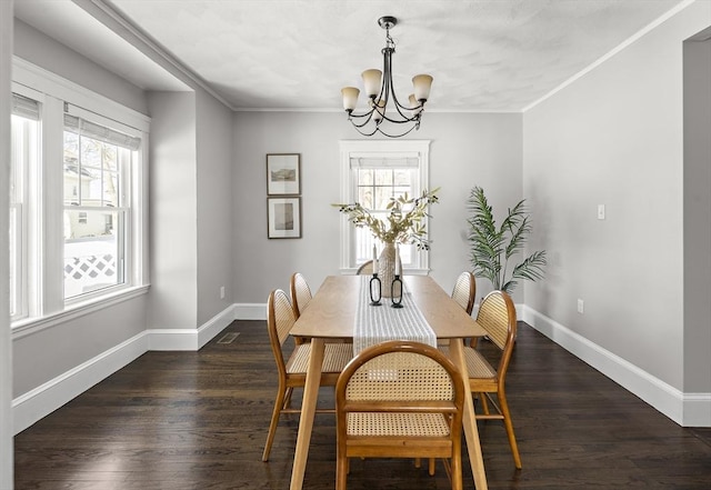 dining space with crown molding, dark hardwood / wood-style floors, and an inviting chandelier