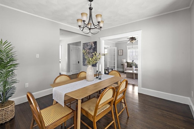 dining area with dark wood-type flooring, crown molding, and ceiling fan with notable chandelier