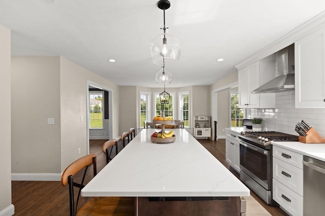 kitchen with appliances with stainless steel finishes, wall chimney exhaust hood, dark wood-style flooring, baseboards, and recessed lighting