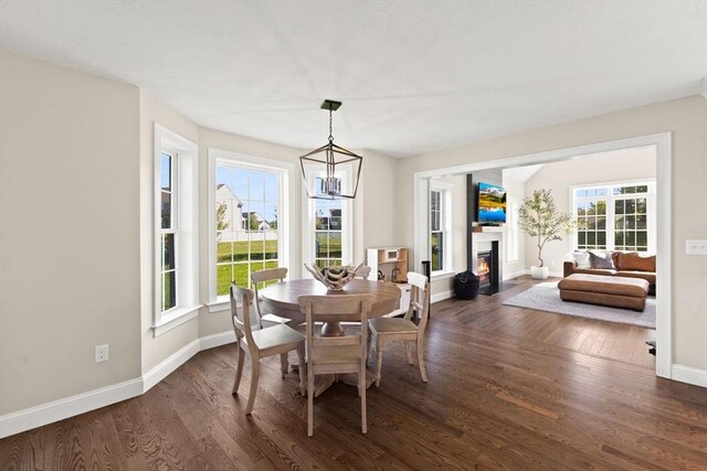 dining room featuring dark wood-style flooring, baseboards, and a glass covered fireplace