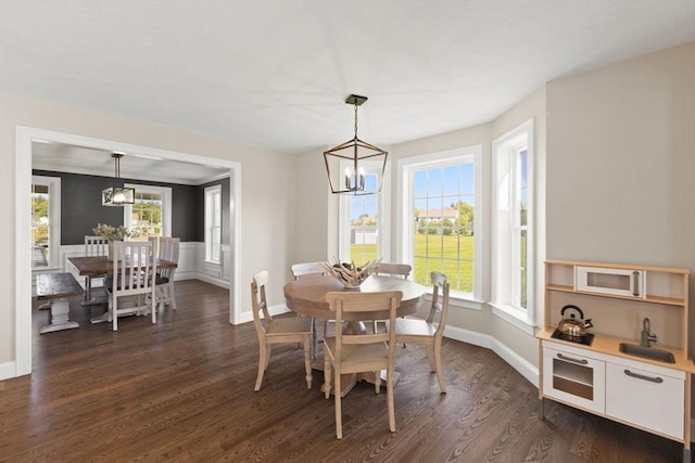 dining area featuring a chandelier, dark wood finished floors, and baseboards
