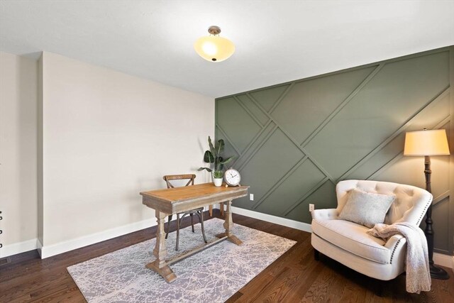 office featuring baseboards, wood finished floors, and a decorative wall