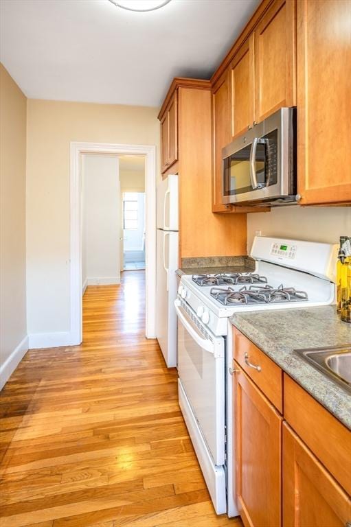 kitchen featuring light stone countertops, white appliances, and light hardwood / wood-style flooring