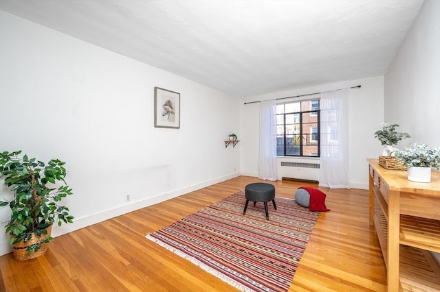 sitting room featuring wood-type flooring and radiator heating unit