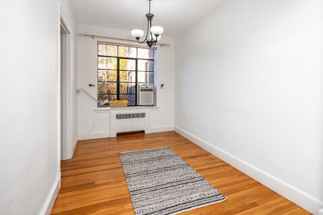 entryway featuring wood-type flooring, radiator heating unit, and a chandelier