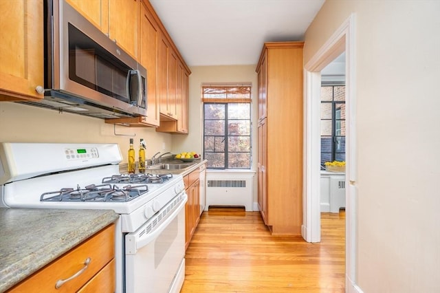 kitchen featuring sink, white range with gas cooktop, radiator, and light wood-type flooring