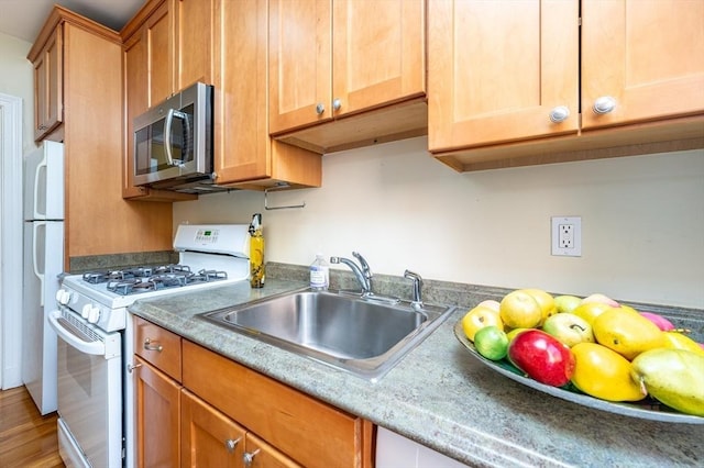 kitchen featuring sink, white appliances, and wood-type flooring