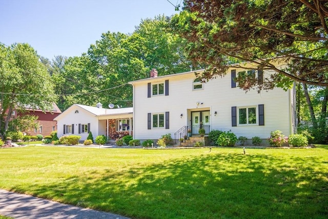 colonial inspired home with a chimney and a front lawn