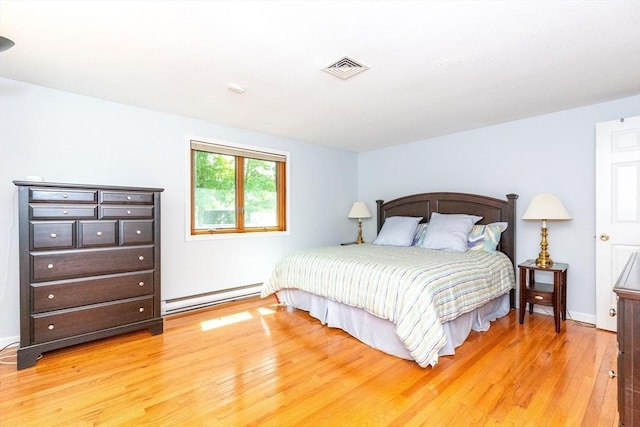 bedroom with visible vents, light wood-style flooring, a baseboard heating unit, and baseboards