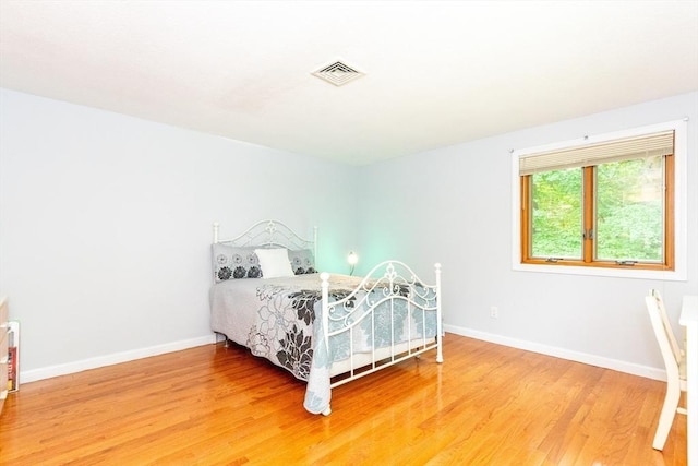 bedroom with visible vents, baseboards, and light wood finished floors