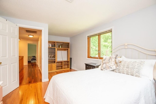 bedroom featuring visible vents, baseboards, and wood finished floors