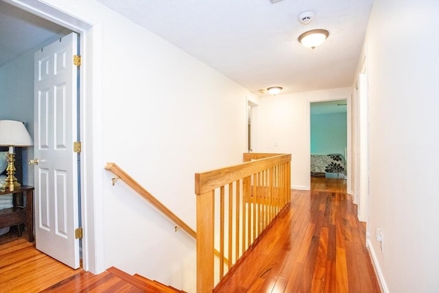 hall with wood-type flooring and an upstairs landing