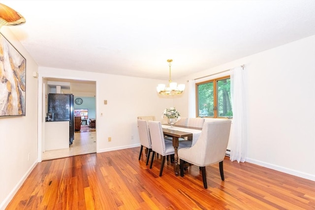dining area featuring a chandelier, wood finished floors, and baseboards