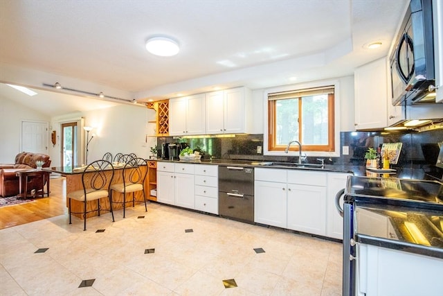 kitchen with tasteful backsplash, a sink, dark countertops, black appliances, and white cabinetry