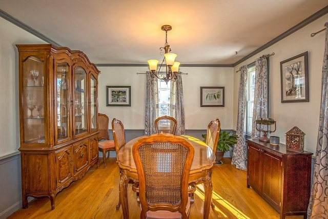 dining room with a notable chandelier, crown molding, and light wood-type flooring