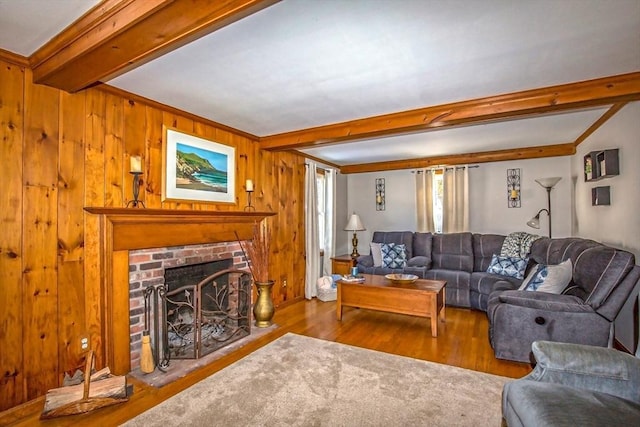 living room featuring hardwood / wood-style flooring, a brick fireplace, wooden walls, and beam ceiling