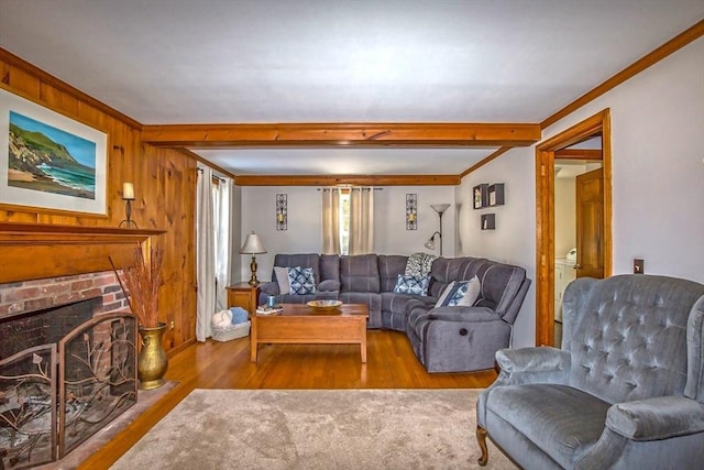 living room featuring crown molding, wooden walls, a fireplace, and light hardwood / wood-style flooring