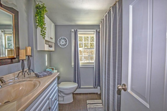 bathroom with a shower with curtain, vanity, toilet, and a baseboard heating unit