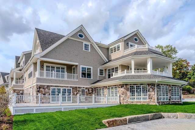 rear view of property featuring a yard and a balcony