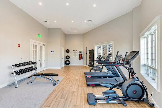 workout area featuring a high ceiling, wood-type flooring, and french doors