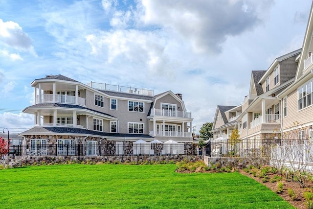 rear view of property with a balcony and a yard