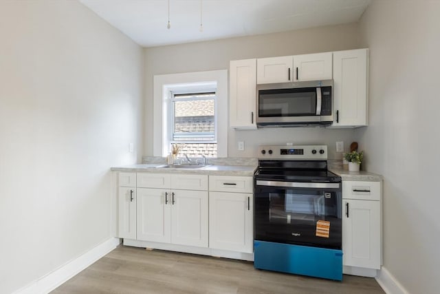 282 Palmer St, New Bedford, MA 02740 - kitchen featuring stainless steel appliances, a sink, white cabinets, light countertops, and baseboards