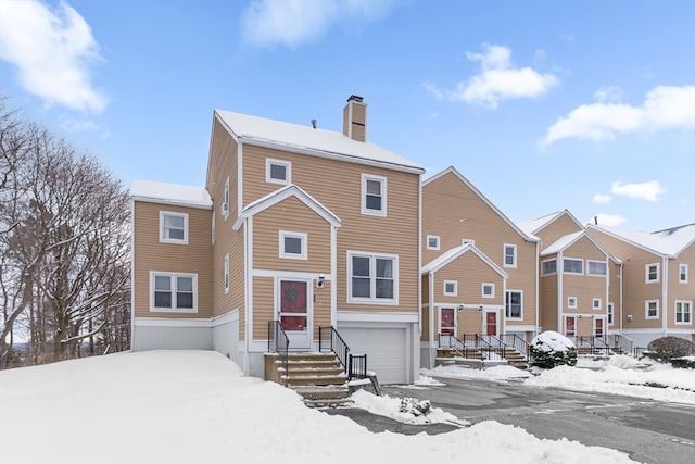 view of front of property featuring an attached garage, a chimney, and a residential view