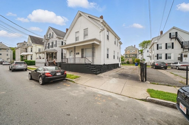193 Division St, New Bedford, MA 02744 - view of front of house featuring covered porch, a residential view, a chimney, and uncovered parking