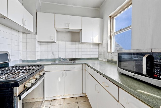 kitchen with backsplash, stainless steel appliances, sink, white cabinets, and light tile patterned flooring