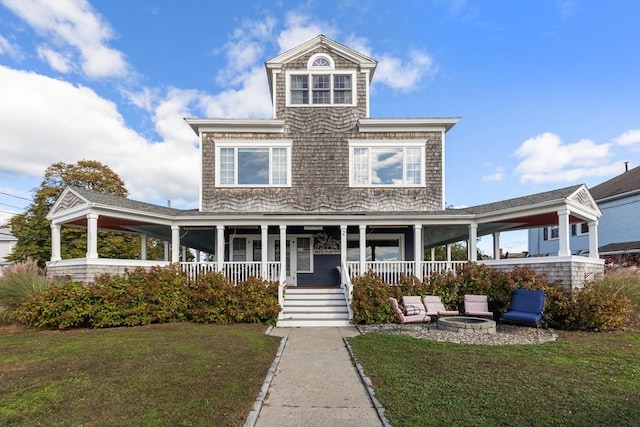 view of front of home featuring a fire pit, covered porch, and a front yard