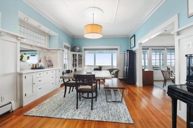 dining space with ornamental molding, light hardwood / wood-style flooring, and a baseboard heating unit