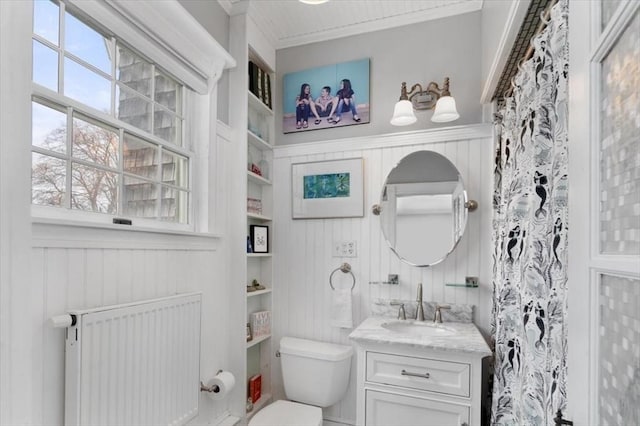 bathroom with radiator, ornamental molding, vanity, built in features, and toilet