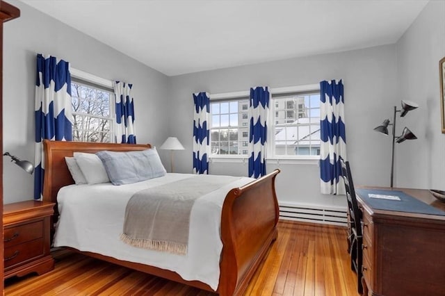 bedroom with light wood-type flooring and a baseboard heating unit