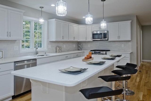 kitchen with a breakfast bar area, sink, white cabinets, and appliances with stainless steel finishes