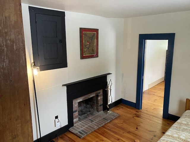 unfurnished bedroom featuring a brick fireplace, baseboards, and wood finished floors