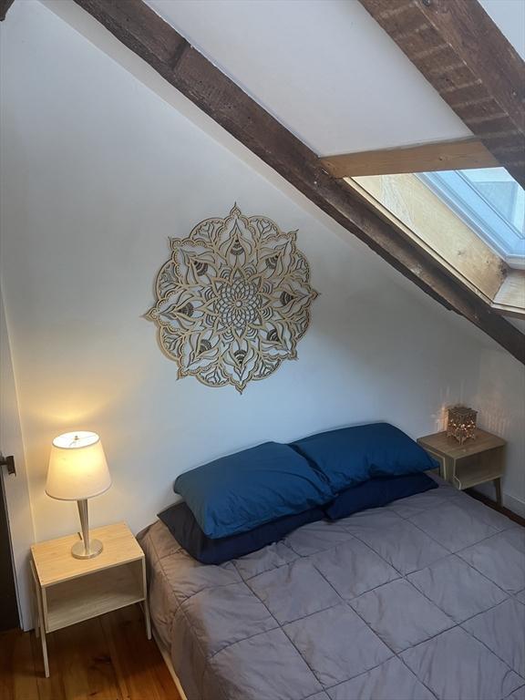 bedroom featuring lofted ceiling with skylight and wood finished floors