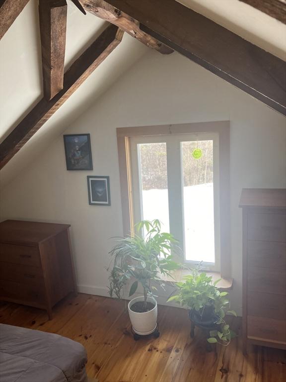 interior space featuring lofted ceiling with beams, hardwood / wood-style flooring, and baseboards