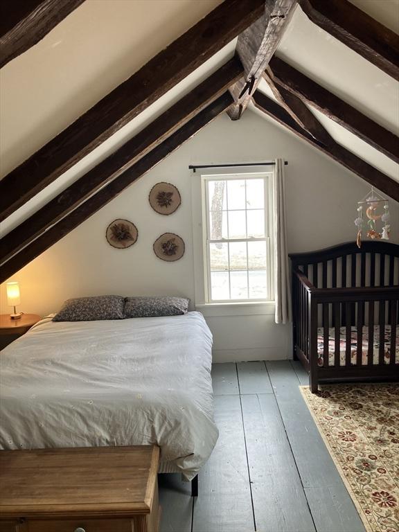 bedroom with vaulted ceiling with beams and wood finished floors