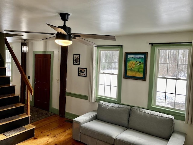 living area featuring ceiling fan, stairway, hardwood / wood-style flooring, and a healthy amount of sunlight