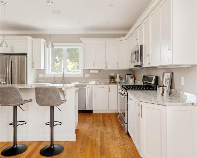 31 Neponset Ave, Boston, MA 02131 - kitchen featuring stainless steel appliances, white cabinetry, light wood-style floors, a kitchen breakfast bar, and ornamental molding