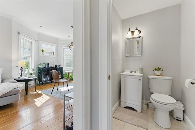 bathroom featuring baseboards, ornamental molding, and toilet