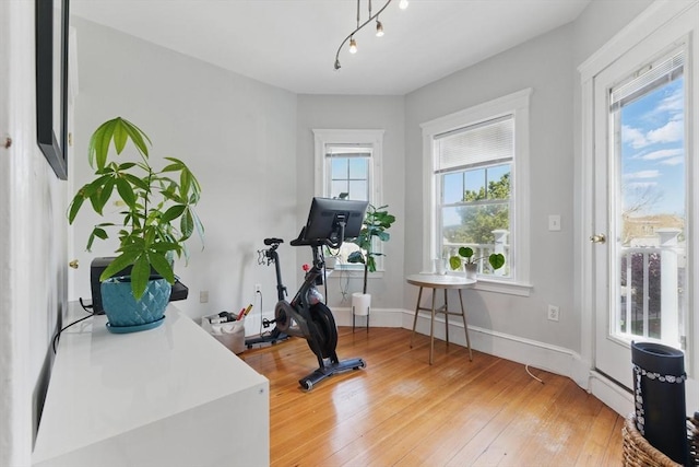 exercise area with baseboards and light wood-type flooring
