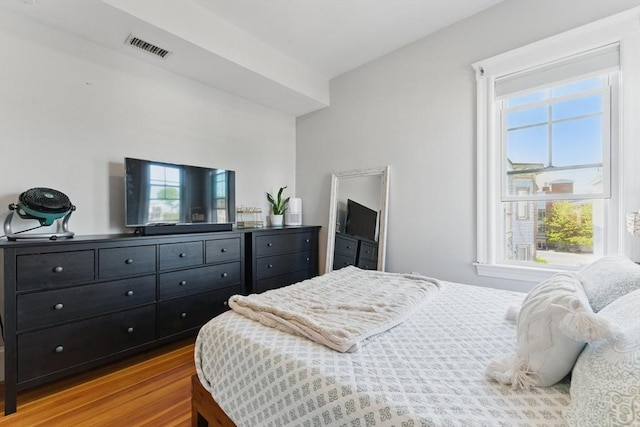 bedroom featuring visible vents, wood finished floors, and multiple windows