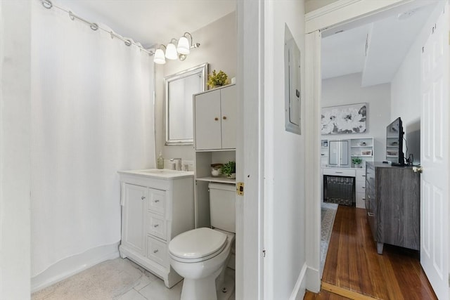 bathroom featuring vanity, toilet, baseboards, a shower with shower curtain, and electric panel