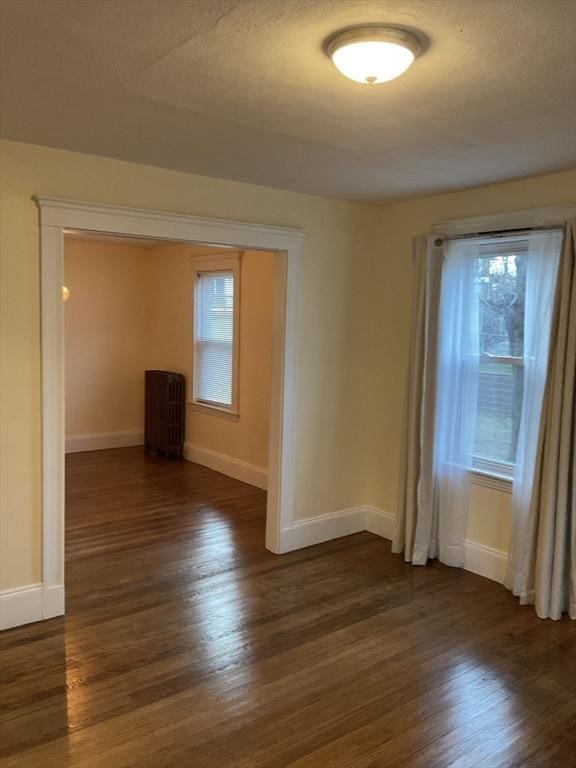 spare room with a textured ceiling and dark hardwood / wood-style floors