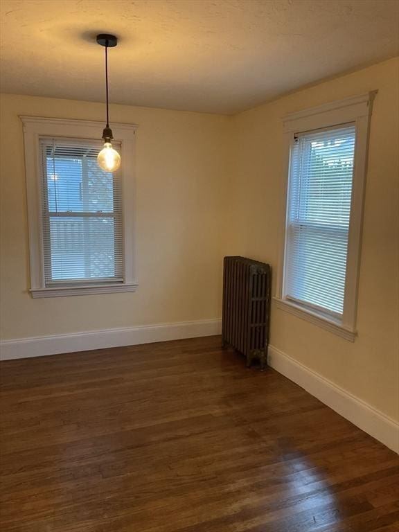 unfurnished room with radiator heating unit and dark wood-type flooring