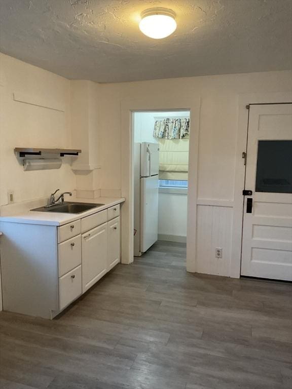 kitchen with sink, light hardwood / wood-style flooring, a textured ceiling, white fridge, and white cabinetry