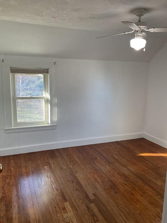 empty room featuring a textured ceiling, ceiling fan, dark wood-type flooring, and vaulted ceiling