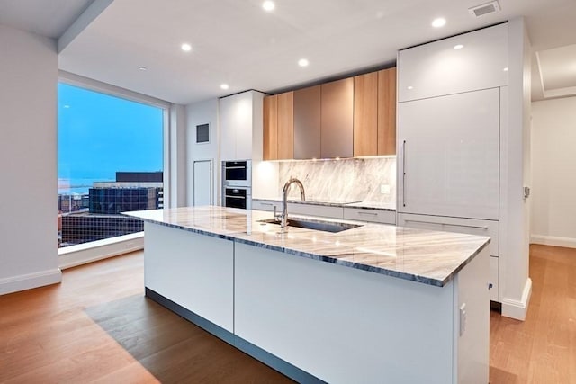 240 Devonshire St Unit 4012, Boston, MA 02110 - kitchen with light wood-style flooring, modern cabinets, recessed lighting, backsplash, and light stone countertops